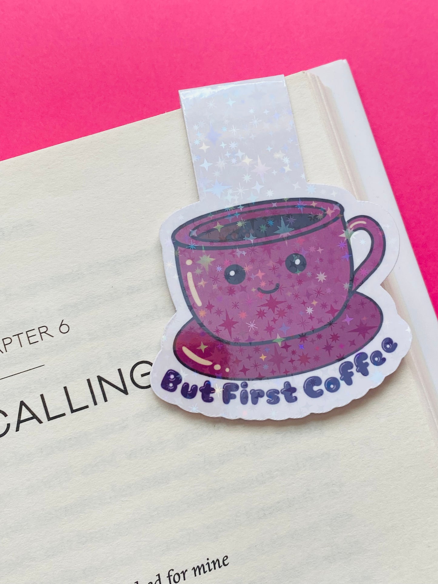 Glossy white Cardstock magnetic bookmark on a Pink Background with the image of a pink cup and saucer with the text caption “But First Coffee”