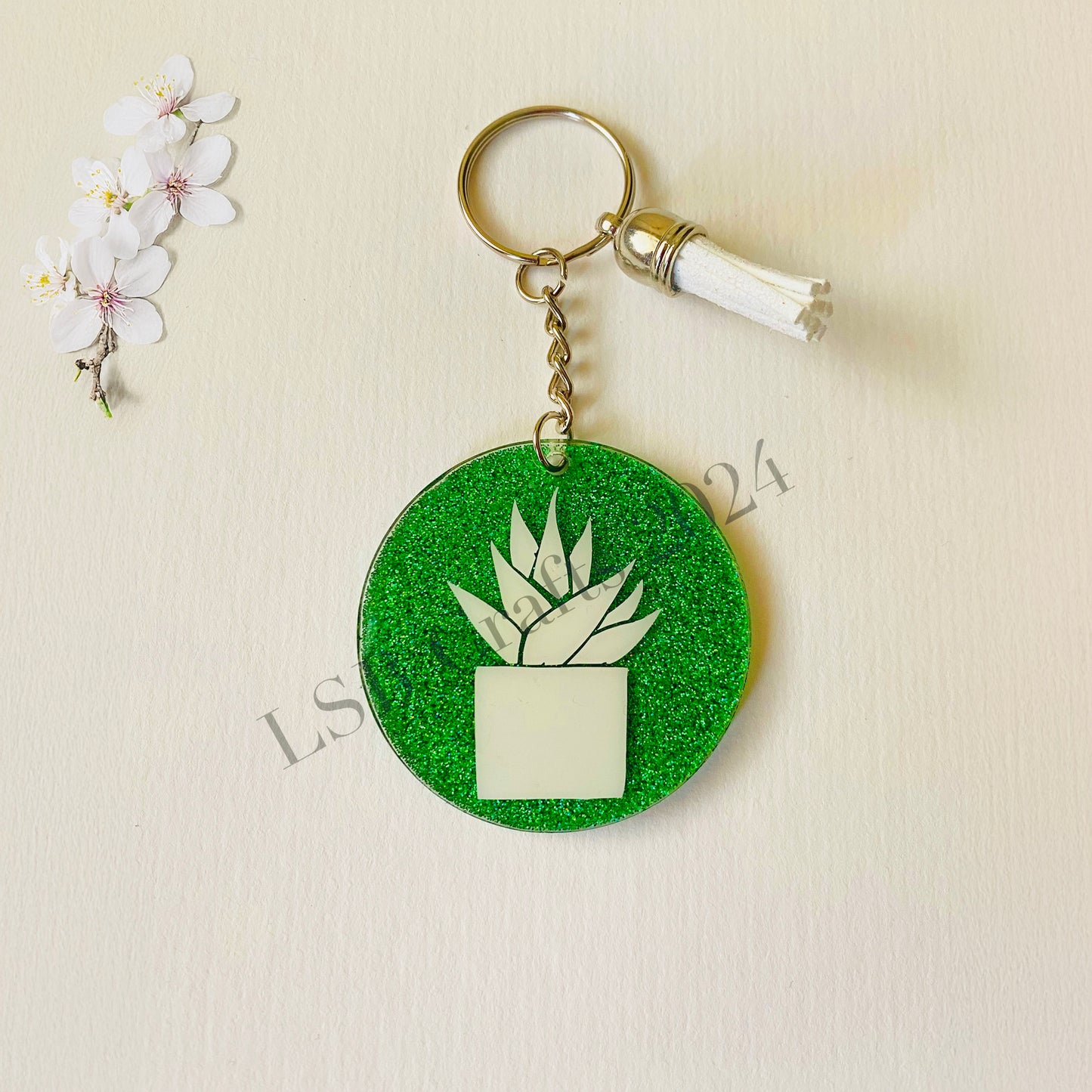 Plain Green Background (glossy) with White Vinyl (glossy) and White Tassel.
Design details on the acrylic keychain is personalised with the image of an Aloe Vera plant.