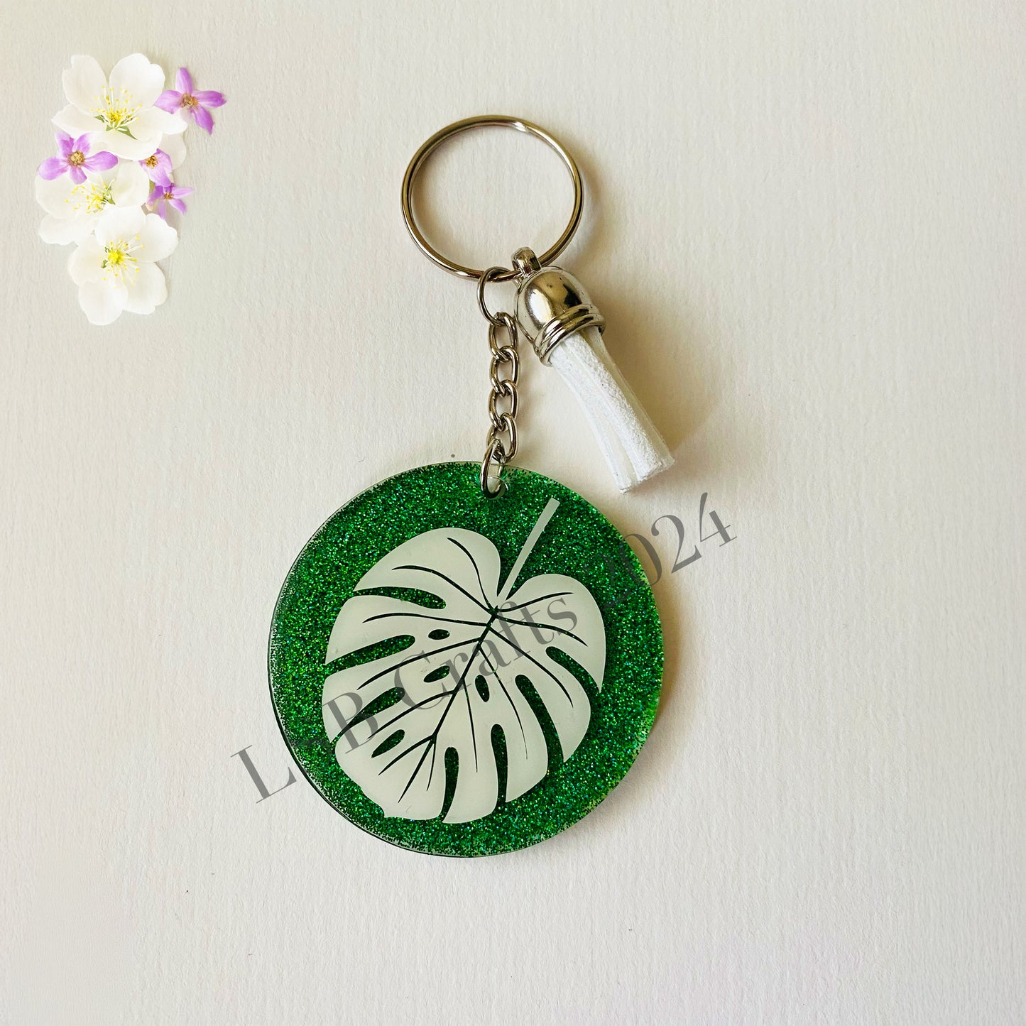 Plain Green Background (glossy) with White Vinyl (glossy) and White Tassel.
Design details on the acrylic keychain is personalised with the image of a Monteserra leaf.