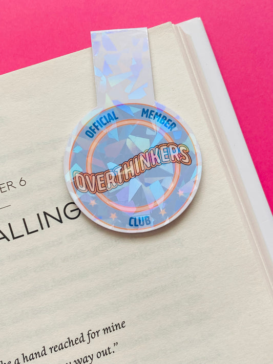 Glossy white Cardstock magnetic bookmark with the image a blue and orange circle and text caption of “Overthinkers Club”