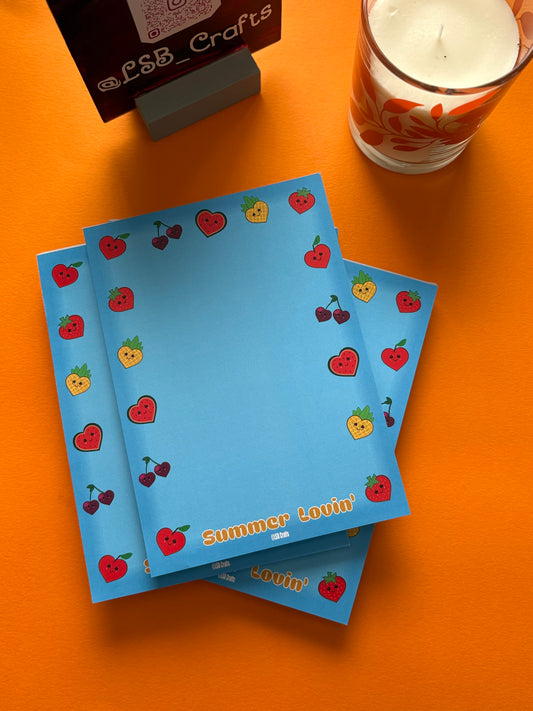 A5 sized notepad in Blue with the image of heart shaped kawaii fruits in the border.